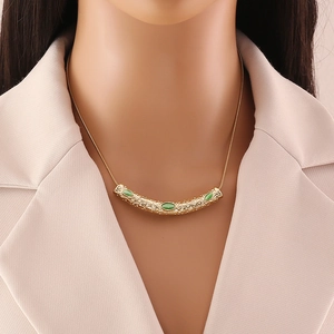 Irregular textured gold necklace with three green gemstones worn by a model