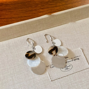 Detail of acrylic geometric earrings with tortoise shell texture on linen background