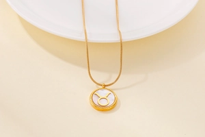 Macro view of golden Taurus zodiac pendant with white shell inlay and delicate snake chain