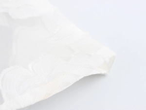 Close-up of white lace fabric featuring delicate floral jacquard and sheer mesh texture