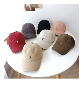 Flat lay of multiple washed cotton baseball caps with number 7 embroidery in seven colors