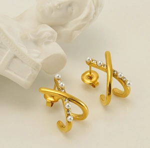 Close-up of gold-finish cross pearl earrings featuring miniature rhinestones and vintage style