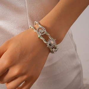 Detail of woven rope bracelet with embossed silver sunflower charm and bohemian aesthetic