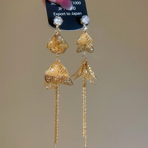 Détail de boucles d'oreilles dorées à glands avec pétales évidés, zircon et argent 925