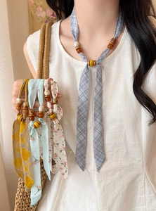 Close-up detail of printed chiffon necklaces with wooden beads in various floral patterns