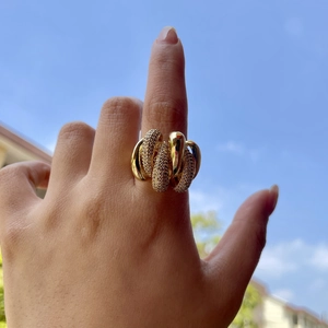 Irregular twisted gold ring with sparkling diamond pavé crystals shown against blue sky