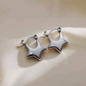 Polished silver star earrings displayed on soft beige silk fabric with elegant lighting