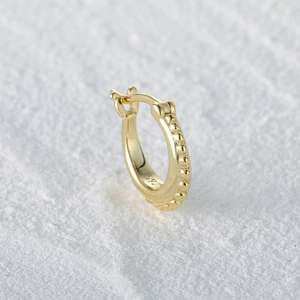 Macro shot of S925 sterling silver gold hoop earrings with small bead textures on stone