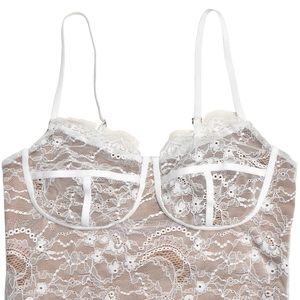 Close-up of white lace floral pattern and satin trim on backless camisole dress