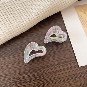 Macro shot of two iridescent heart-shaped mini hair claws on a rustic wooden background