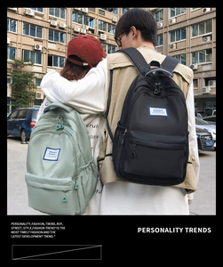 Outdoor view of two high-capacity nylon backpacks in black and green for students