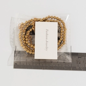 Detail of gold beaded chain with lobster clasp and extension chain on sizing card