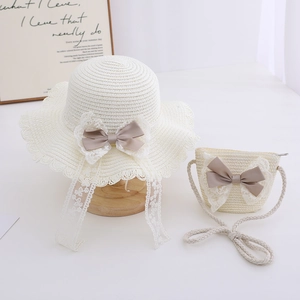 Detail of children's straw hat and bag with delicate lace edges and satin bows