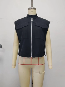Detail of black utility vest featuring a stand collar, metal zipper, and dual flap pockets