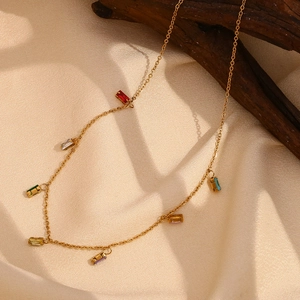 Gros plan détaillé du collier doré avec charmes en zircon colorés sur tissu de soie