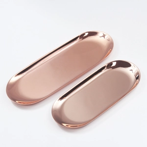 Detailed view of two oval rose gold stainless steel trays with polished mirror finish