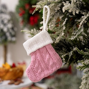 Detailed knit of pink Christmas stocking with white cuff hanging on a festive tree