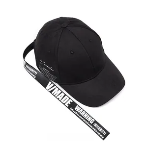 Detail of black cotton baseball cap featuring long strap with white V/MADE text