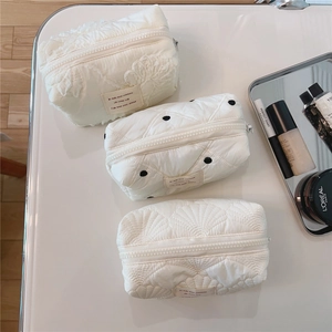 Vue détaillée des trousses à maquillage matelassées crème avec dentelle et pois
