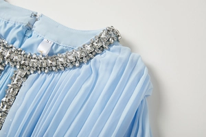 Détail macro de la robe bleu ciel avec strass cousus main et plis sur le décolleté
