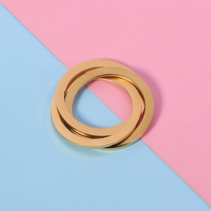 Macro detail of three interlocking golden geometric rings on a pastel background