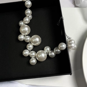 Detail of French vintage necklace featuring mixed sizes of white pearls on black box