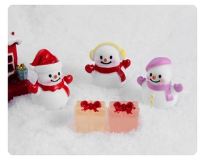 Figurine di pupazzi di neve in resina con sciarpe e scatole regalo su sfondo innevato