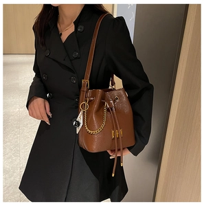 Détail d'un sac seau marron en similicuir avec chaîne dorée et fermeture à cordon