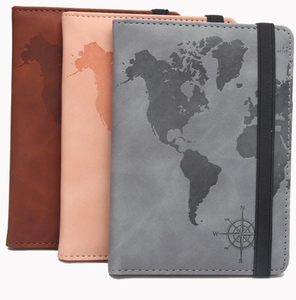 Detail view of leather passport holders with world map embossing and elastic strap closure