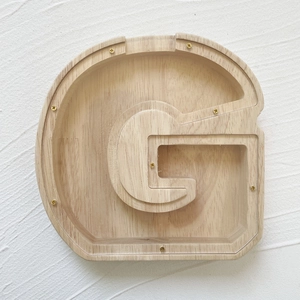 Macro detail of G-shaped oak wood money box with natural grain and golden screw fixings