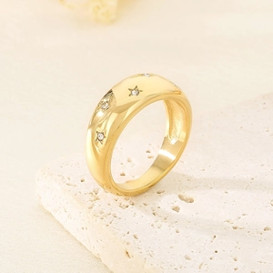 Macro shot of gold-plated stainless steel wide ring featuring star engravings and zircons