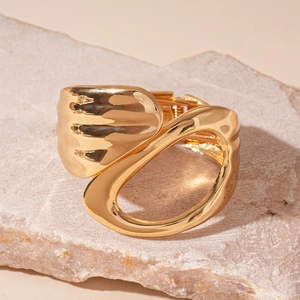 Macro detail of minimalist gold-plated geometric hair clip on a natural stone background