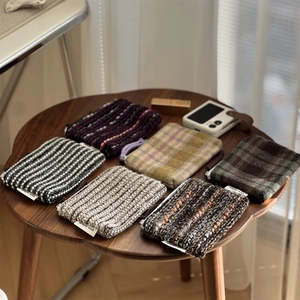 Close-up of assorted plaid tweed mini coin pouches and small cosmetic bags on a wood table