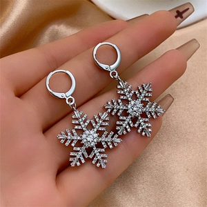 Macro shot of silver snowflake drop earrings with micro-pave crystals on hand