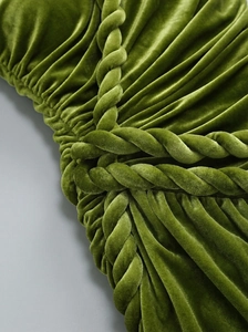 Macro detail of green velvet fabric featuring an elegant twisted knot and pleated design