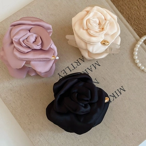 Vista dettagliata di mollette per capelli a fiori di seta in rosa, beige e nero su un libro