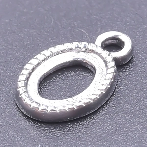 Macro shot of silver stainless steel oval bezel pendant with serrated edges for DIY jewelry