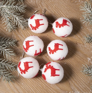Close-up of six white plush Christmas balls with red reindeer prints on wooden surface
