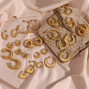 Collection of gold-plated stainless steel earrings on silk and stone textures