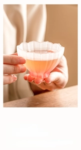 Detailed view of a frosted lotus-shaped glass teacup with a soft pink gradient finish