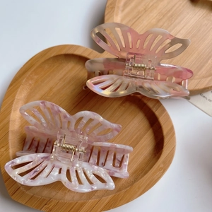 Detail view of butterfly acetate hair claws in pink marble and orange gradient finishes