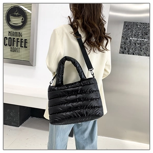 Detail of black quilted puffer tote bag with thick handles and wide nylon shoulder strap
