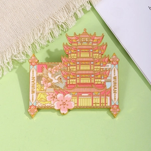 Close-up of golden enamel Yellow Crane Tower magnet with pink cherry blossom details