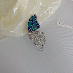 Close-up of enamel butterfly brooch featuring blue-green gradient wings and silver cutouts