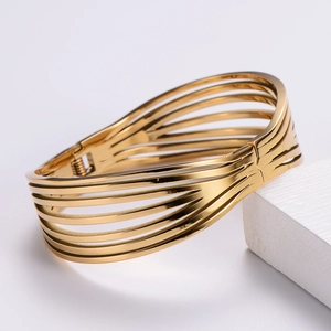 Détail d'un bracelet ajouré multicouche plaqué or posé sur un support géométrique