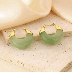 Detailed close-up of golden U-shaped earrings with translucent green resin drops