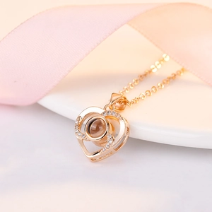 Macro detail of rose gold heart pendant with projection stone and elegant pink ribbon