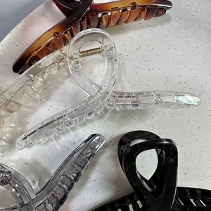 Close-up of four 13cm large hair claw clips in tortoise, clear, grey and black colors