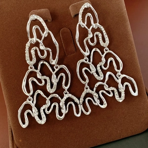 Macro view of silver geometric layered earrings with rhinestones on velvet stand