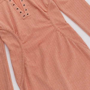 Dettaglio dell'abito in maglia con scollo a V, occhielli metallici e trama rosa corallo